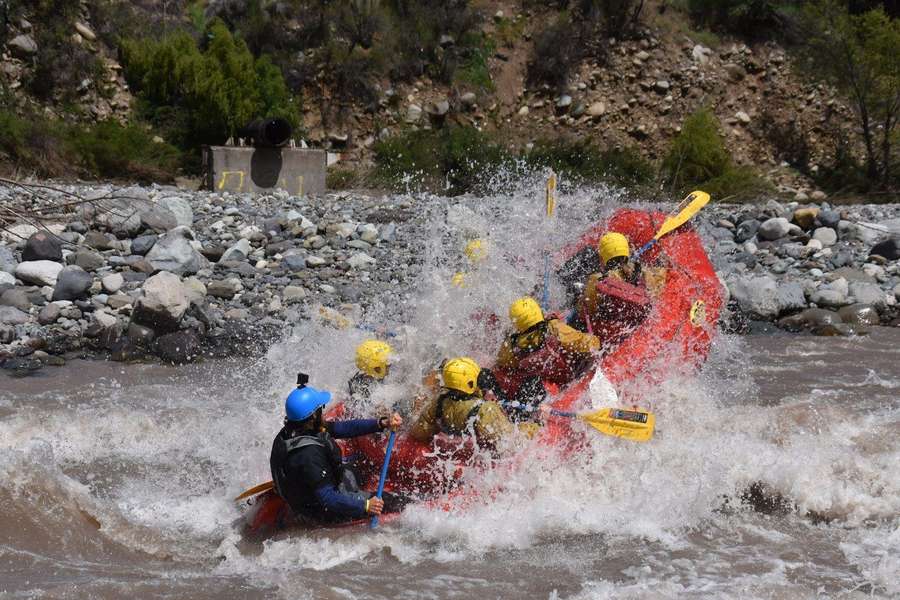 Balsa de rafting con pasajeros cruzando un rápido del Río Maipo
